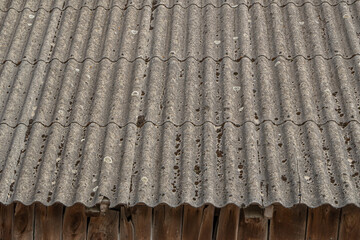 Old weathered asbestos cement roof sheets with signs of decay and aging. Hazardous building...