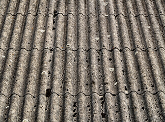Close-up of damaged asbestos corrugated roofing sheets. Toxic material with visible wear, holes,...