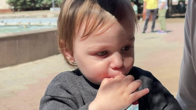 Toddler eats pouch outside while walking with dad