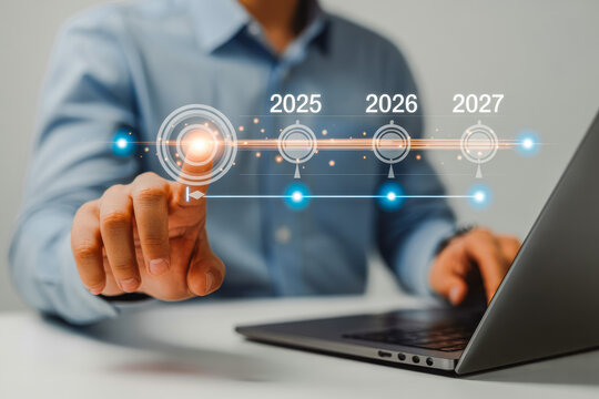 A person interacts with a digital timeline projected above a laptop, highlighting future years 2025, 2026 to 2027, symbolizing business planning and strategic foresight in technology.