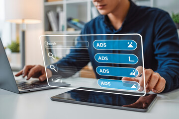 A person in an office uses a laptop for digital marketing. A virtual screen displays a search bar with "ADS" icons, representing online advertising and search engine optimization strategies.