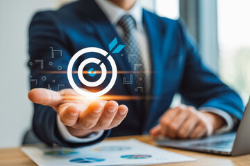 Businessman in suit holding virtual target symbol, symbolizing precision and goals. Ideal for business strategy or digital marketing themes. Laptop and documents visible, enhancing professionalism.