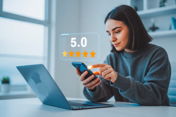 A woman using a smartphone rates an app with a 5-star review rating, sitting at a desk with a laptop. The modern setting highlights technology, customer satisfaction, and positive feedback.