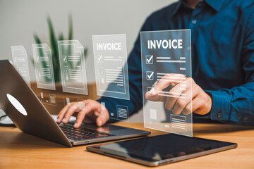 A person interacts with a futuristic digital invoice interface, utilizing a laptop and tablet. The image illustrates modern technology used for efficient electronic billing and financial management.