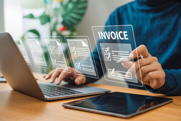 A person uses a stylus on a transparent invoice hologram interface near a laptop and tablet. The setting is modern, showcasing digital technology for efficient invoicing.