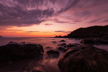 Fototapeta premium Rocky shore at sunset with long exposure sea and colorful clouds