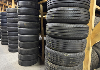Rows of used tires are organized on wooden shelves in a warehouse, showcasing a clean and efficient...