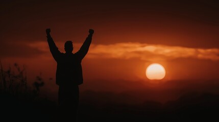 Silhouette of a triumphant figure celebrating at sunset over a mountain landscape with vibrant hues of orange and purple illuminating the horizon
