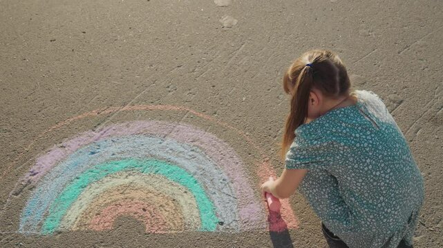 child kid girl baby draws rainbow pavement chalk, childhood dream. Little girl creates rainbow, Using colorful chalks, Her world is bright, Simple joys matter, Skirt touching ground, Concentration