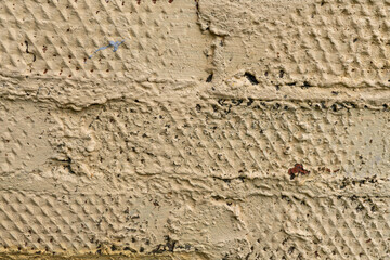Texture of rough beige painted brick wall with weathered surface