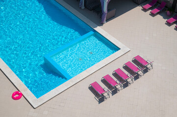 Outdoor pool with water and sun loungers. Place for relaxation and swimming, top view