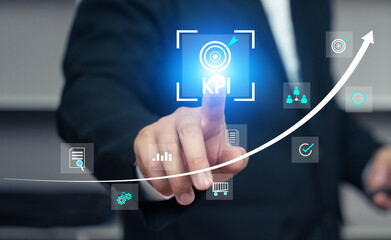 Businessman touches a glowing KPI (Key Performance Indicator) icon on a virtual screen with various business and financial icons. A rising arrow graph in the background signifies performance improveme