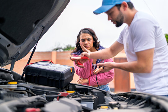 Mechanic helping woman with car battery problems