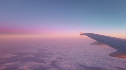 Fototapeta premium Soft pastel tones in the sky during sunrise with partial wing view from airplane seat