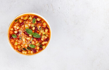 Italian vegetarian soup with vegetables, pasta on white background. Minestrone soup. Italian food. Top view. Copy space.