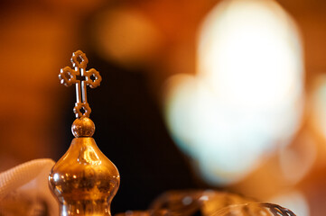 Golden Orthodox cross of crown with blurred background in warm ambient light.