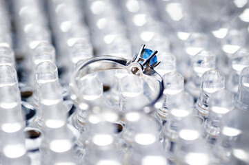 A beautiful silver ring featuring a blue gemstone displayed against a bright textured metallic background, symbolizing elegance, luxury, and timeless charm.