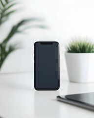 Black smartphone on white desk with plants and tablet in background