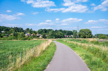 Bending cycling road through the meandering fields at the banks of the river Dyle in Aarschot, Flemish Brabant, Belgium