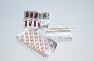 tablets, thermometer and capsules on a white background. treatment for colds and viral diseases....