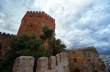 Historic Red Brick Tower and Stone Wall Under Cloudy Sky