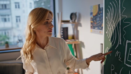 College professor explaining formulas on chalkboard closeup. Lady educator 