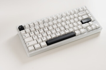 Modern mechanical keyboard on white desk as background. Minimal style and design keyboard. Custom build keyboard with black and white cap. Close up