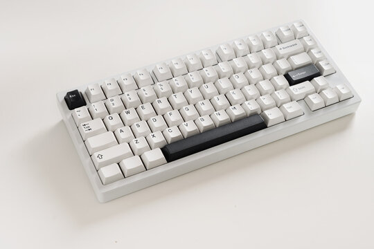 Modern mechanical keyboard on white desk as background. Minimal style and design keyboard. Custom build keyboard with black and white cap. Close up
