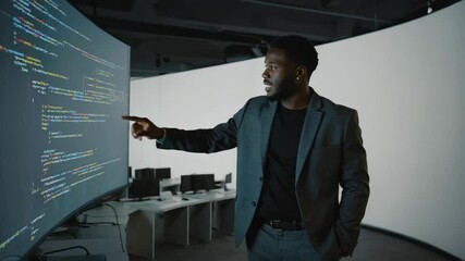 Professional African American man working with real-time code in a futuristic tech hub. Concept of intelligent systems and IT leadership. - Powered by Adobe