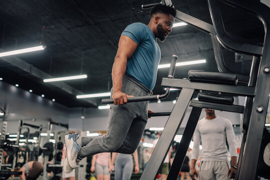 Determined male athlete performing dips on parallel bars in gym