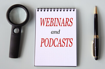 WEBINARS and PODCASTS - words on a black notebook with a magnifying glass and pen in the background