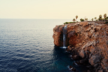 Scenic Ocean Waterfall Cascading from a Rocky Cliffside at Sunset