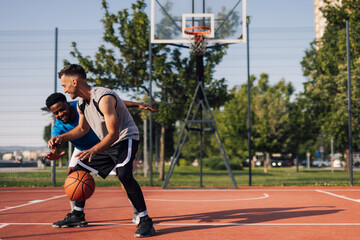 Two young basketball players playing one on one on outdoor court