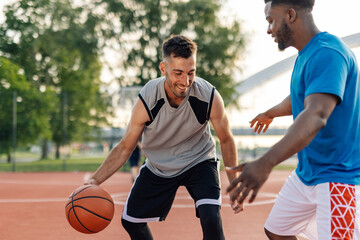 Two male basketball players playing basketball on outdoor court