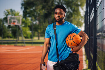 Young basketball player posing on court holding basketball