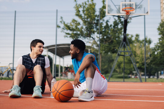 Two basketball players relaxing and talking on court after game