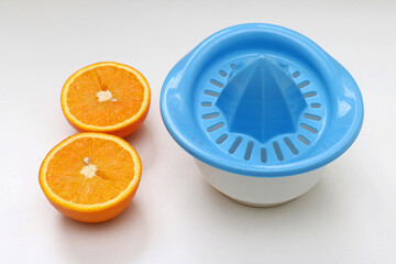 Fresh orange cut in half next to plastic juice squeezer