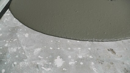 Construction worker leveling wet concrete surface using a trowel, making smooth and even floor