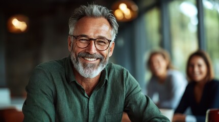 Fototapeta premium A gray-haired man with glasses smiles warmly at the camera, exuding confidence and wisdom in a welcoming environment filled with soft lighting and friendly faces.