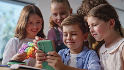 Smiling children playing cellphone sharing joyful moment at school break closeup