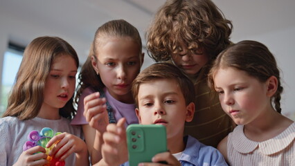 Fototapeta premium Curious children looking smartphone at group activity closeup. Diverse pupils 