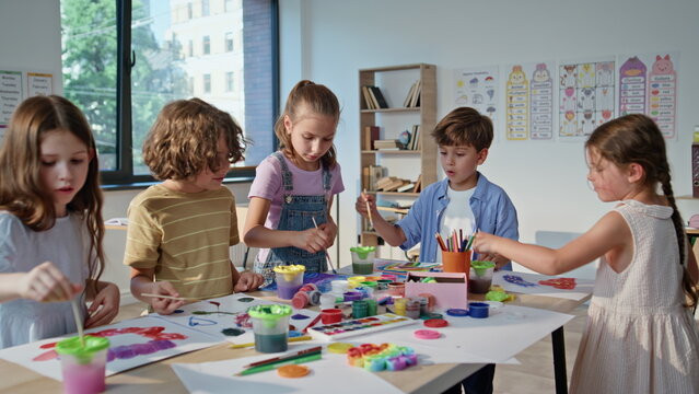 Pupils creating colorful art at collaborative workshop with vibrant materials. 