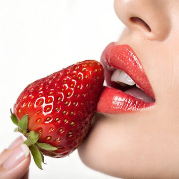 woman with strawberry. woman seductively holds strawberry near lips. woman enjoys taste of strawberry. sweet orgasm. advertisement for adults. food advertisement. sweet strawberry.18+ erotica