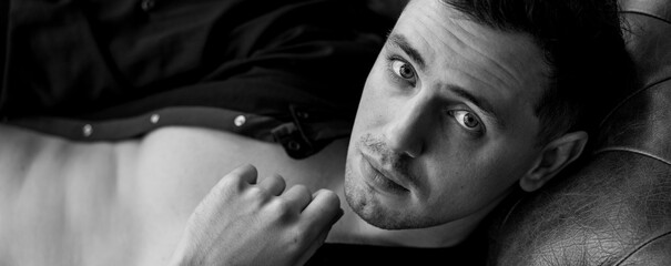 Portrait of a handsome young stylish sexy man in a white shirt, jeans jacket posing in studio with...