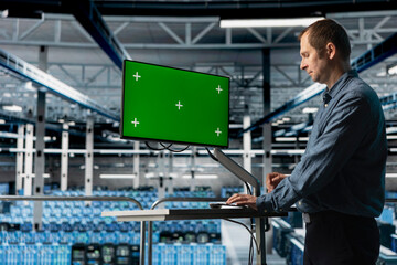Data center admin using green screen PC to do programming, optimizing resource allocation. Man in...