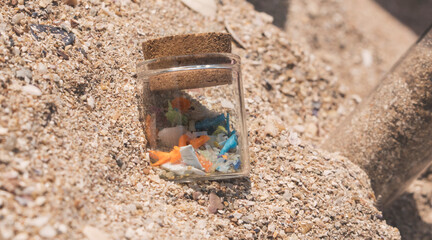 Macro shot of micro plastics in a sample glass container in the sand at the beach. Concept of...