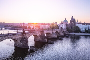 Early morning light bathes Charles Bridge in a golden hue. The iconic Old Town Bridge Tower rises...