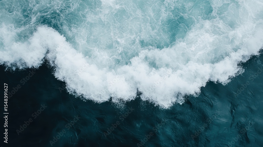 Poster an overhead shot capturing the dynamic movement of waves crashing against the deep blue ocean, prese