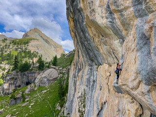 Agile female climber on a colorful and challenging rock wall in the French Alps. Majestic alpine...