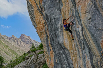 LOW ANGLE VIEW: Climber expertly navigating a massive and textured rock face. Beautiful mountain...